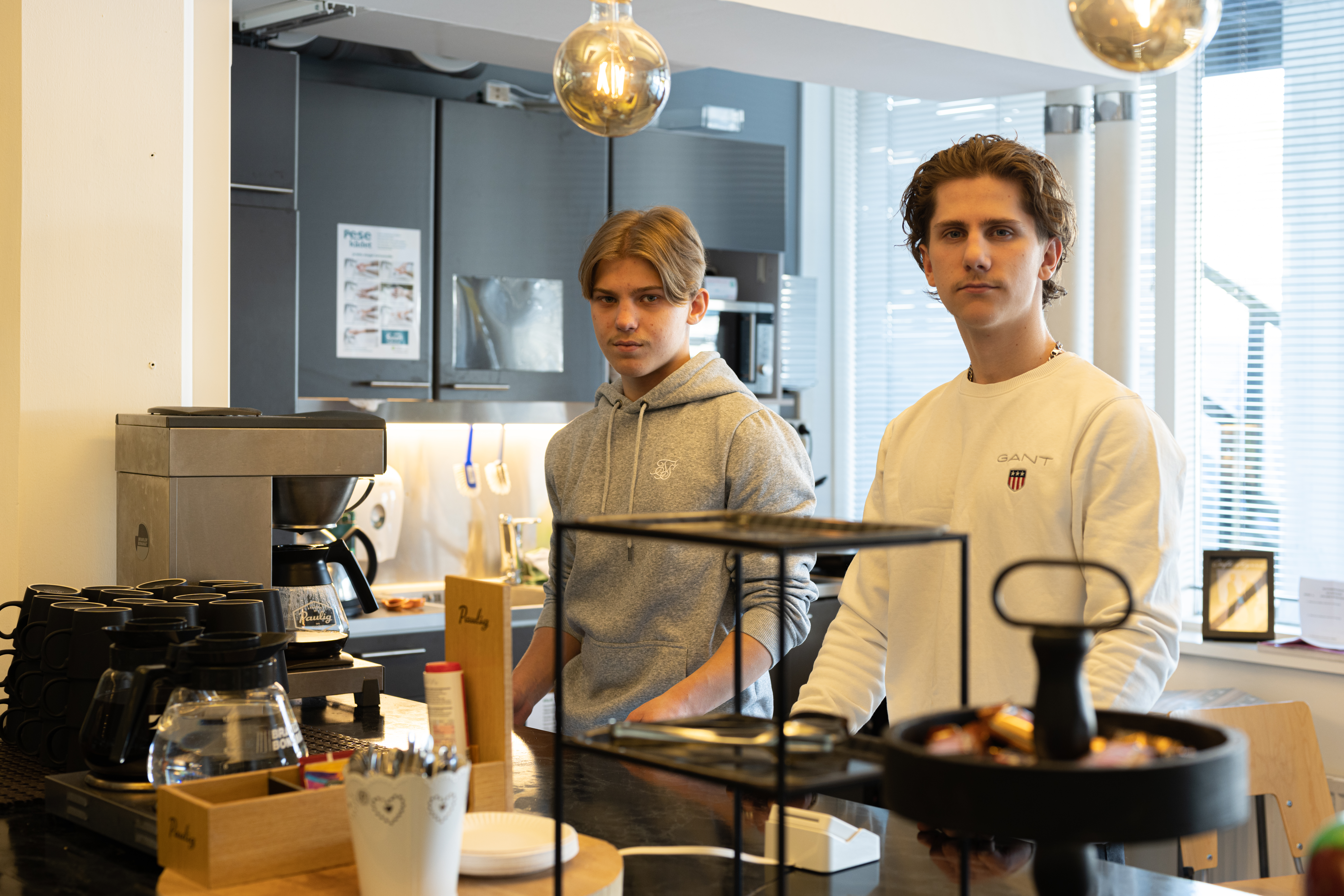 Kaksi liiketoiminnan opiskelijaa seisovat kahvilan palvelutiskin takana.