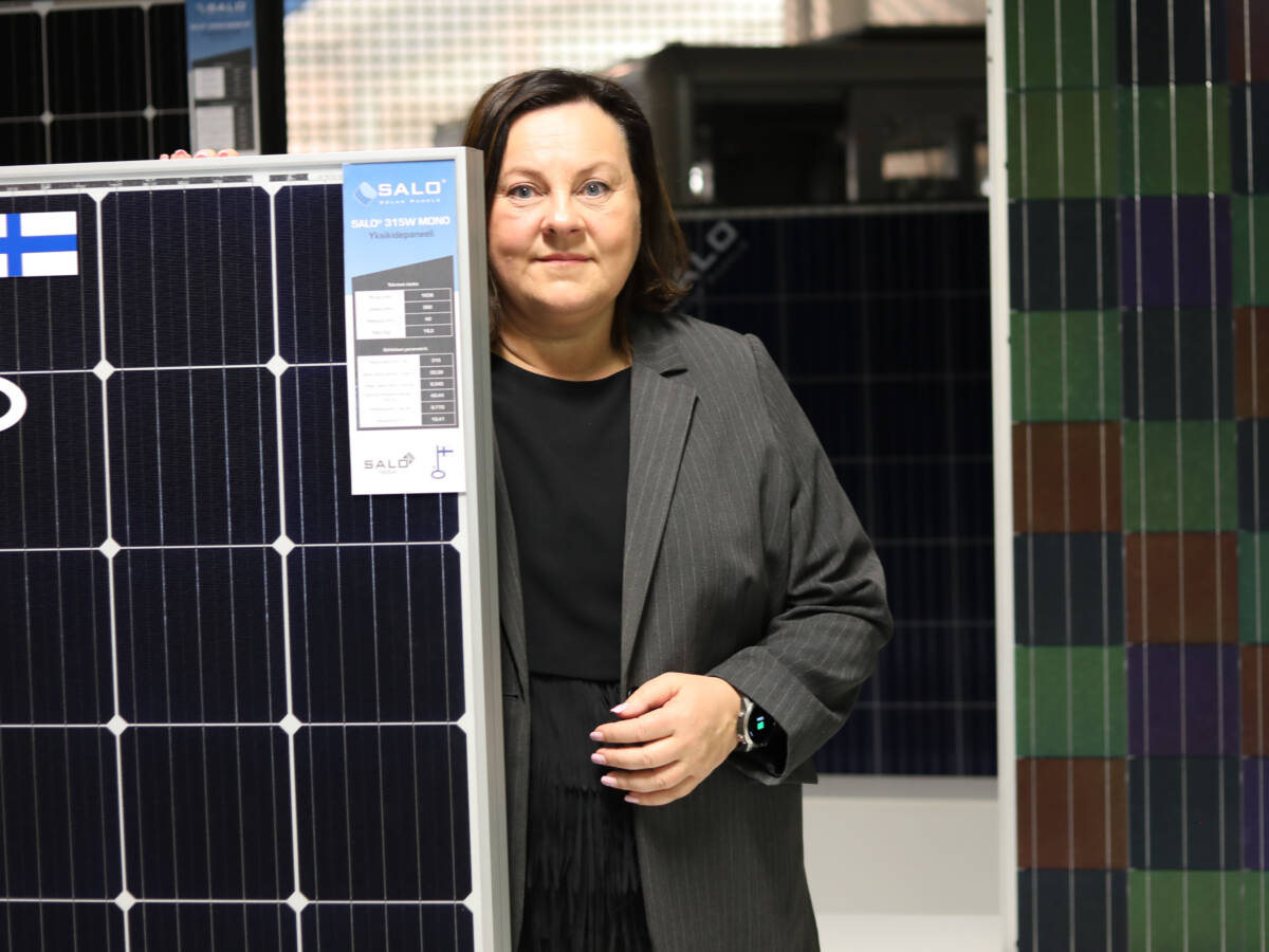 Solar Finland Oyn toimitusjohtaja Anu Areva seisoo aurinkopaneelien kanssa yrityksen tehtaan tiloissa.