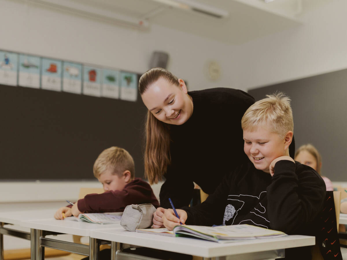 Kasvatus- ja ohjausalan opiskelija tukee lasta oppimistilanteessa luokkahuoneessa.