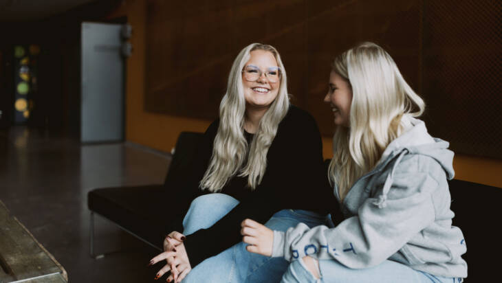 Iloiset opiskelijat keskustelevat Salon seudun ammattiopiston aulatilassa.