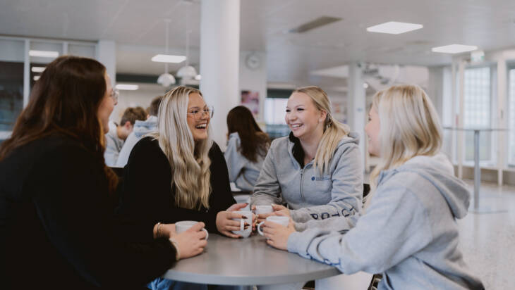 Opiskelijat keskustelevat yhteisöpedagogin kanssa Salon seudun ammattiopiston aulatilassa.