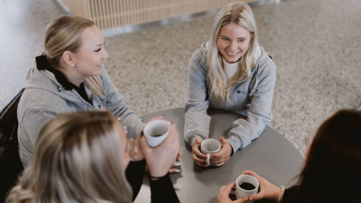 Opiskelijat keskustelevat pöydän ääressä Salon seudun ammattiopistossa.