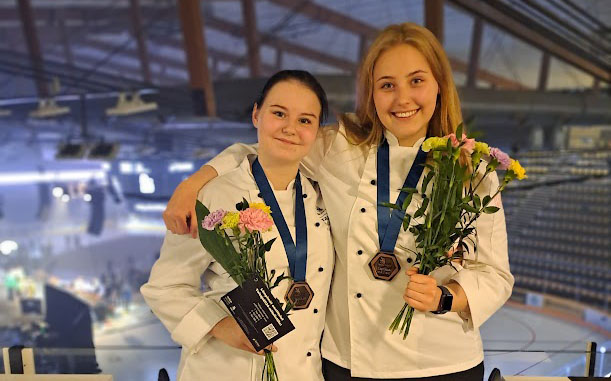 Taitaja 2024 kilpailussa pronssimitalille sijoittuneet Salon seudun ammattiopiston ravintola-alan opiskelijat kukkien ja mitalien kera yhteiskuvassa.