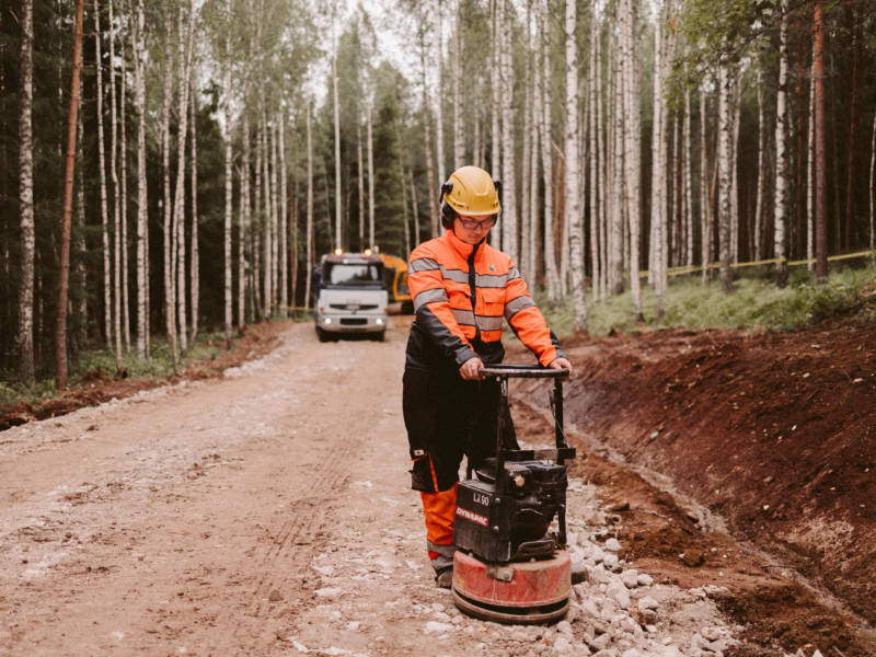 Maarakennusalan opiskelija tasoittaa maata maantiivistäjä koneella harjoittelualueella metsässä.