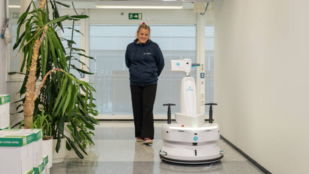 Opiskelija harjoittelee lattianpesurobotin käyttöä käytävällä.