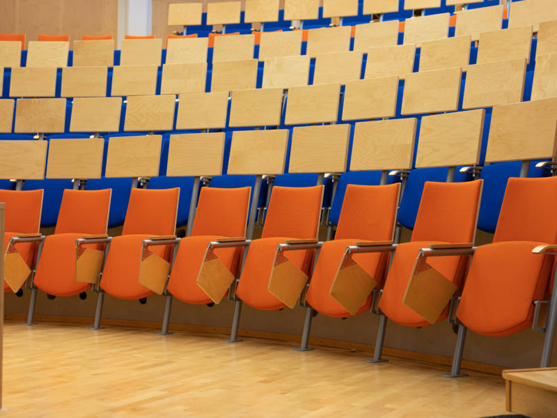 Taitajankadun auditorion oransseja ja sinisiä tuoleja.
